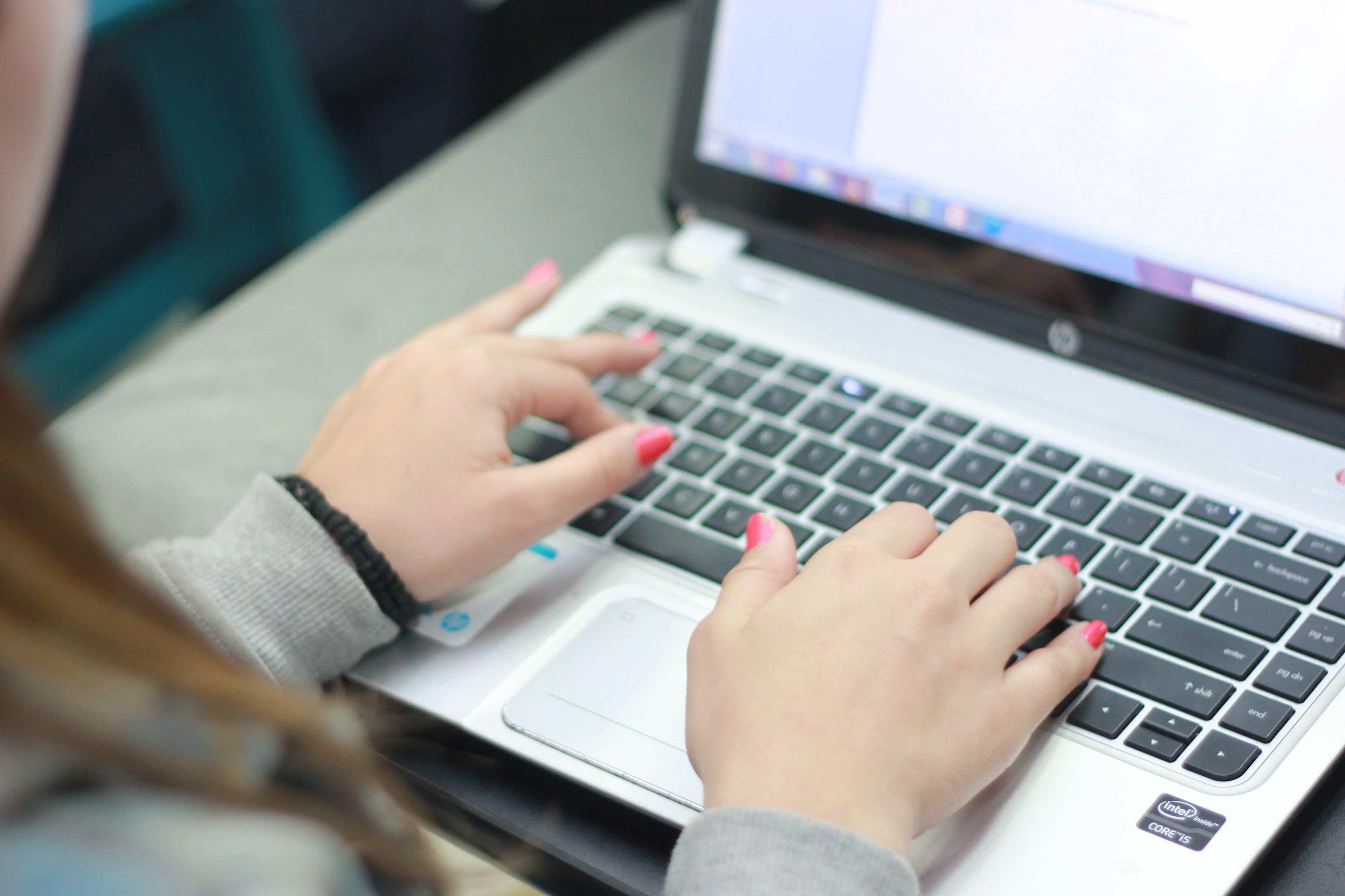 A student typing on a laptop, working through a computer-based practice exam